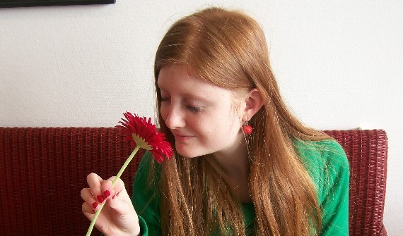 Junge Frau die an einer dufttenden Blume riecht